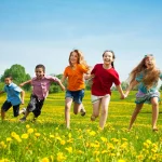 grupo de niños y niñas cogidos de la mano corriendo en campo