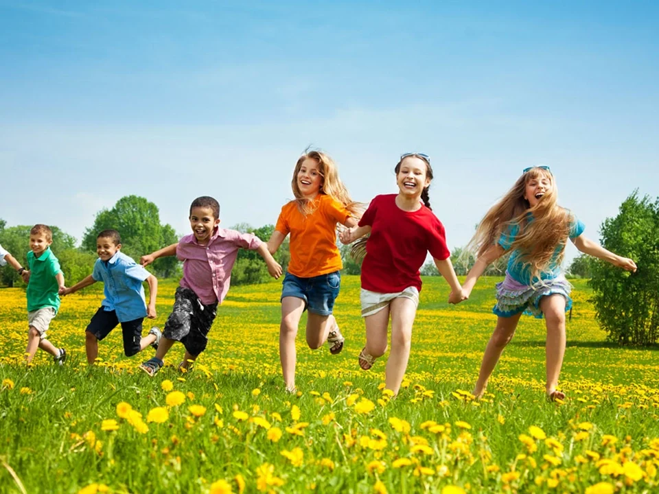 grupo de niños y niñas cogidos de la mano corriendo en campo
